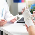 Injured Patient Showing Doctor Broken Wrist And Arm With Bandage